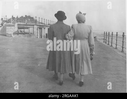 Vista posteriore di due signore che camminano lungo un braccio anteriore non identificato. Foto Stock