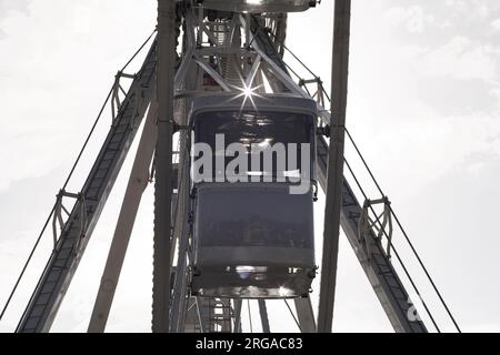 moderna ruota panoramica con cabine chiuse al carnevale con cielo blu senza nuvole sullo sfondo ripresa ravvicinata con grandangolo illuminato Foto Stock