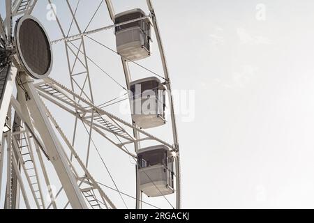 moderna ruota panoramica con cabine chiuse al carnevale con cielo blu senza nuvole sullo sfondo ripresa ravvicinata con grandangolo illuminato Foto Stock