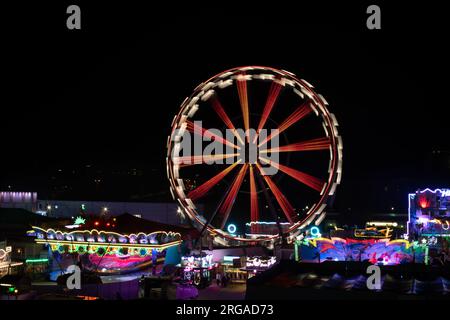 moderna ruota panoramica con cabine chiuse al carnevale con cielo blu senza nuvole sullo sfondo ripresa ravvicinata con grandangolo illuminato Foto Stock