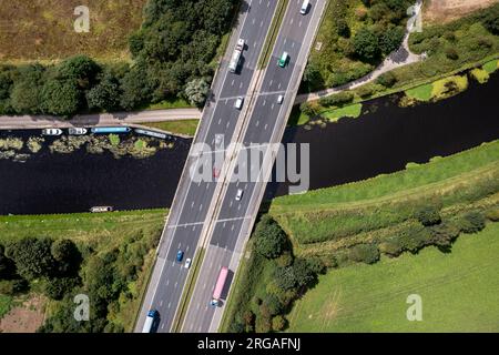 Vista aerea direttamente sopra una trafficata autostrada del Regno Unito passando sopra un fiume o un ponte canale in campagna Foto Stock