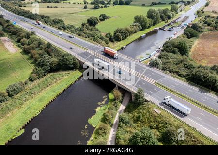 Vista aerea direttamente sopra una trafficata autostrada del Regno Unito che attraversa un fiume o un ponte sul canale in campagna Foto Stock