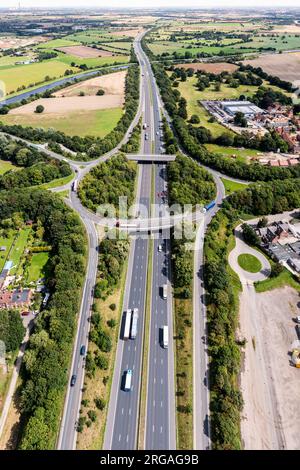 Panorama aereo verticale direttamente sopra un trafficato incrocio stradale che attraversa la campagna sull'autostrada M62 in direzione est verso Hull nel Regno Unito Foto Stock