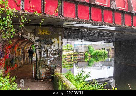 Un uomo solitario cammina attraverso il tunnel pedonale lungo il Rochdale Canal ad Ancoats Manchester. Foto Stock