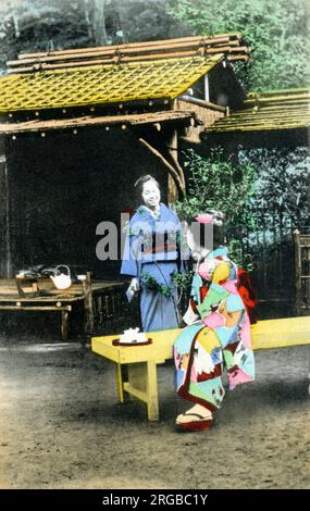 Due donne giapponesi in costume tradizionale che prendono il tè in un giardino. Foto Stock