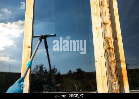 Vista ritagliata dell'attrezzatura per le mani delle donne per lavare e pulire la finestra dall'esterno Foto Stock