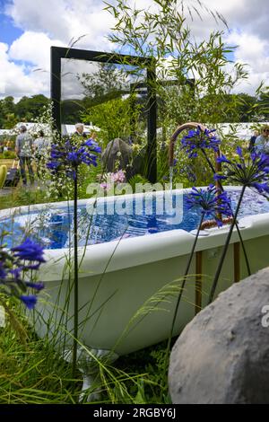 Vasca da bagno con letto rialzato, bambù e agapanthus (ingresso al concorso lungo confine) - RHS Tatton Park Flower Show Showground, Cheshire Inghilterra, Regno Unito. Foto Stock