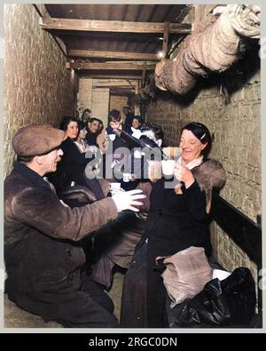 Rifugiandosi sottoterra durante il Blitz a Islington, Londra; una donna versa bevande per coloro che la circondano Foto Stock