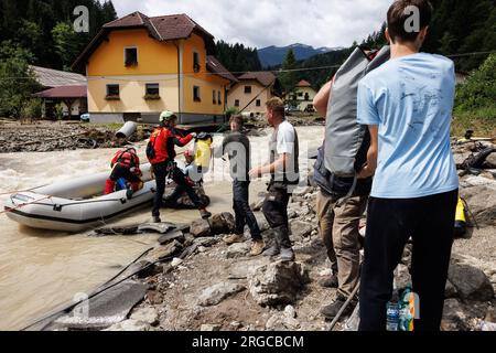 Raduha, Slovenia. 8 agosto 2023. Le persone e il servizio di soccorso in montagna formano una catena umana per gestire gli effetti personali delle persone che vengono evacuati dall'altra parte del fiume in barca a Raduha, dopo che le grandi inondazioni hanno colpito due terzi del paese giorni fa. Sono stati avviati sforzi di risanamento e salvataggio dopo le grandi inondazioni in Slovenia. Alcune aree della valle del fiume Savinja sono ancora tagliate fuori dal resto del mondo. Il danno è enorme. Credito: SOPA Images Limited/Alamy Live News Foto Stock