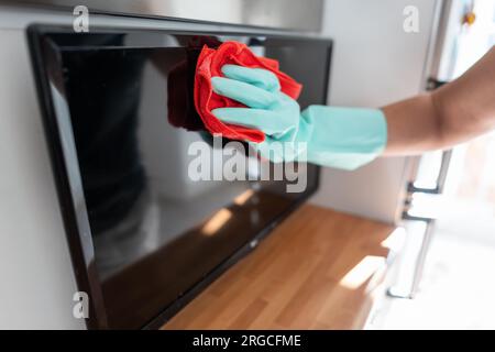 Mano di donna con guanti che svolge le attività di pulizia in cucina. Foto Stock