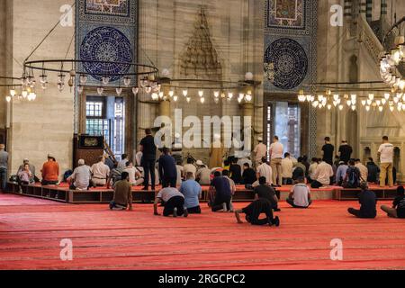 Istanbul, Turchia, Turkiye. Uomini riuniti di fronte al Mihrab per le preghiere di metà giornata nella Moschea di Solimano, la magnifica Moschea di Suleymaniye. Foto Stock