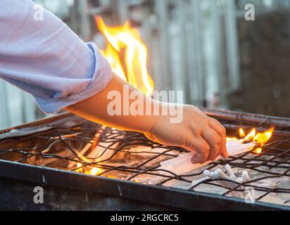 Presso il santuario cattolico, accanto all'iconico Belfry di Dumaguete. Il Santo adoratore mette candele brucianti sulla parte superiore della griglia, come grandi fuochi d'oro Foto Stock