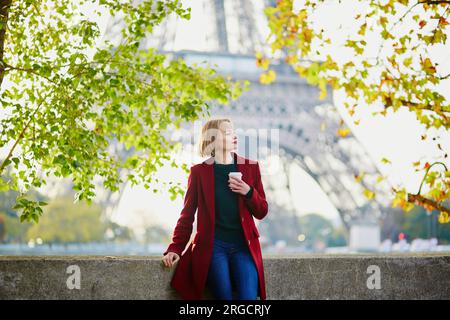 Bella giovane donna francese con un sacco di foglie autunnali colorate vicino alla Torre Eiffel a Parigi in un giorno d'autunno Foto Stock