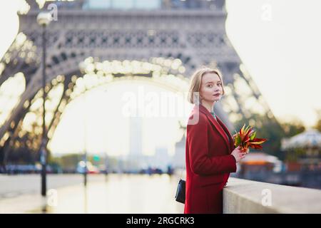 Bella giovane donna francese con un sacco di foglie autunnali colorate vicino alla Torre Eiffel a Parigi in un giorno d'autunno Foto Stock