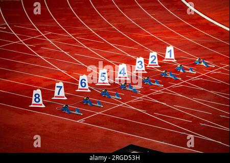 Inizio della gara sprint. Numeri e blocchi di partenza sulla pista rossa. Stadio di atletica leggera. Foto di rilevamento e campo. Numeri di partenza sulle piste di atletica. Foto Stock