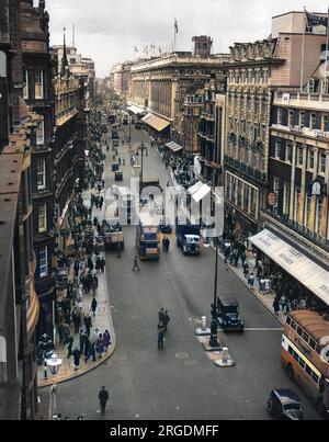 Oxford Street, la principale via dello shopping di Londra - una vista aerea che mostra autobus e acquirenti che affollano il marciapiede. Il tempio del commercio, Selfridges, con bandiere che volano, può essere visto in lontananza. Foto Stock