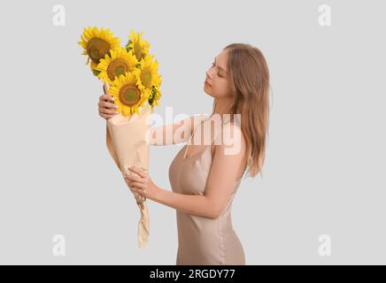 Giovane donna con bouquet di splendidi girasoli in carta su sfondo chiaro Foto Stock