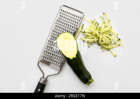 Zucchine verdi fresche e grattugia su fondo bianco Foto Stock