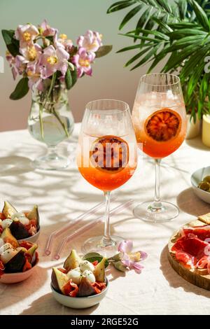 cocktail aperol spritz, su una tovaglia di lino rosa pallido, ombre, luce del sole, drink estivo in bicchiere Foto Stock