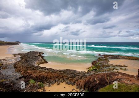 Fraser Island K'gari, piscine di Champagne su una spiaggia di 75 miglia, oceano acquatico e cielo tempestoso sopra la sabbia e la formazione rocciosa, Queensland, Australia Foto Stock