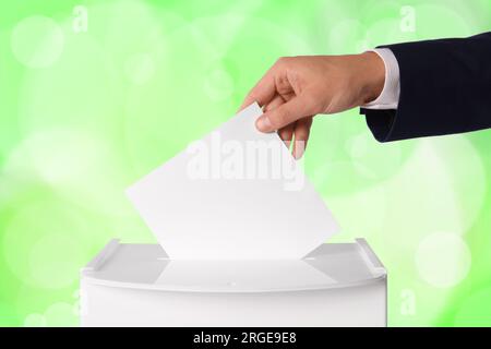 Uomo che mette il suo voto nelle urne su sfondo a colori, primo piano Foto Stock