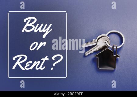 Chiavi con il trinket a forma di casa e parole Acquista o noleggia su sfondo blu, vista dall'alto Foto Stock