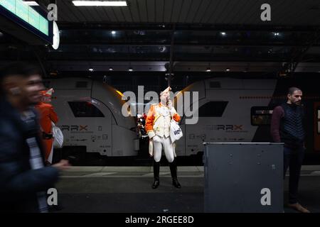 Foto di persone vestite in costume per il Carnevale di Colonia in piedi sulla piattaforma di Koln Hbf, con un accento su un uomo vestito come una guardia che usa la h Foto Stock