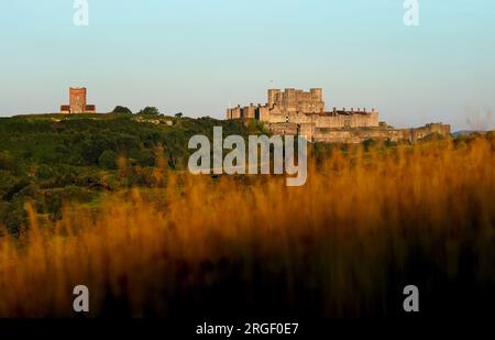 La chiesa di St Mary in Castro e il castello di dover sono bagnati dal sole mentre il sole sorge su dover nel Kent. Data foto: Mercoledì 9 agosto 2023. Foto Stock