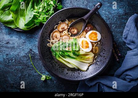 Zuppa di noodles asiatici di ramen miso con shiitake, uovo e cavolo pak choi su sfondo scuro Foto Stock