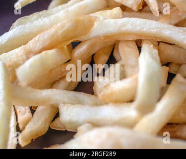 Patatine fritte: Fotografia ravvicinata che mostra patatine fritte fresche e perfettamente dorate su uno sfondo scuro. L'attenzione è posta in modo esperto Foto Stock