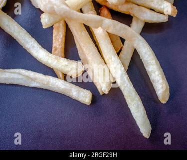 Patatine fritte: Fotografia ravvicinata che mostra patatine fritte fresche e perfettamente dorate su uno sfondo scuro. L'attenzione è posta in modo esperto Foto Stock