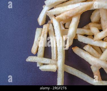 Patatine fritte: Fotografia ravvicinata che mostra patatine fritte fresche e perfettamente dorate su uno sfondo scuro. L'attenzione è posta in modo esperto Foto Stock
