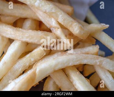 Patatine fritte: Fotografia ravvicinata che mostra patatine fritte fresche e perfettamente dorate su uno sfondo scuro. L'attenzione è posta in modo esperto Foto Stock