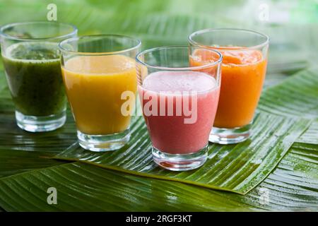 Assortimento di frullati di frutta tropicale fresca sulle foglie di banana verde Foto Stock