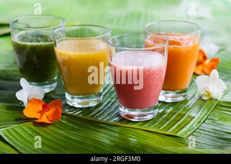 Assortimento di frullati di frutta tropicale fresca sulle foglie di banana verde Foto Stock