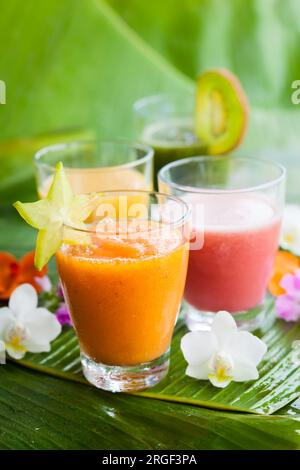 Assortimento di frullati di frutta tropicale fresca sulle foglie di banana verde Foto Stock