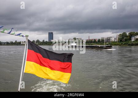 Nave da carico sul Reno, riva del Reno nel distretto di Muelheim, bandiera tedesca su una barca da escursione, Colonia, Germania. Frachtschiff auf dem Rhein, R. Foto Stock