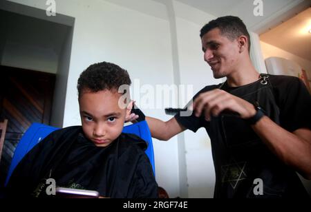 salvador, bahia, brasile - 27 agosto 2022: barber utilizza una macchina per tagliare i capelli di un bambino nella città di Salvador. Foto Stock