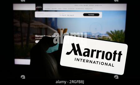 Persona in possesso di un cellulare con il logo della società alberghiera americana Marriott International Inc. Sullo schermo davanti alla pagina Web. Concentrarsi sul display del telefono. Foto Stock