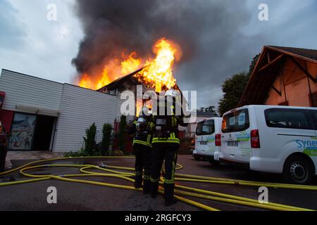 Wintzenheim, Francia. 9 agosto 2023. I vigili del fuoco spengono un incendio in una sistemazione per le vacanze. Undici persone erano scomparse dopo l'incendio. Secondo il ministro degli interni francese Darmanin, il sito ospita persone disabili. La prefettura ha scritto che un gruppo di adulti di Nancy stava soggiornando al rifugio per le vacanze. Credito: Patrick Kerber/dpa/Alamy Live News Foto Stock