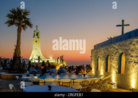 IOS, Grecia - 17 agosto 2018: Vista delle festività locali accanto a una pittoresca cappella e un incredibile tramonto a iOS Grecia Foto Stock