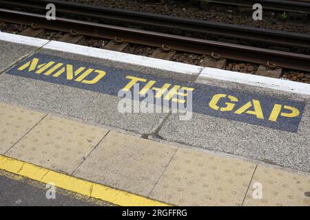 Prestare attenzione al messaggio di avvertenza GAP sul bordo della piattaforma della stazione ferroviaria. Segnale di sicurezza per il trasporto ferroviario Foto Stock