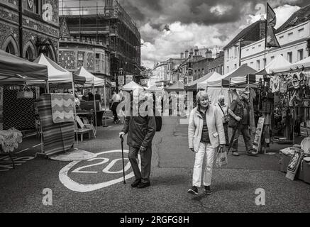 Una coppia anziana cammina nel fine settimana attraverso il mercato dell'antiquariato e dell'artigianato di High Street, Winchester, Hampshire, Regno Unito. Il mercato si svolge il sabato e. Foto Stock