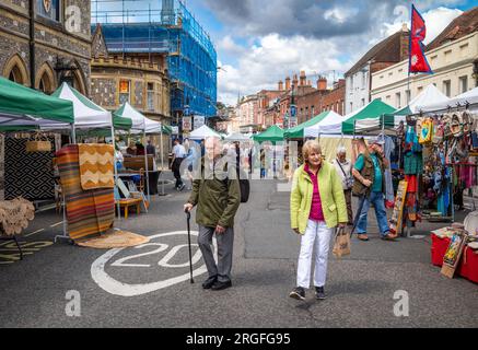 Una coppia anziana cammina nel fine settimana attraverso il mercato dell'antiquariato e dell'artigianato di High Street, Winchester, Hampshire, Regno Unito. Il mercato si svolge il sabato e. Foto Stock