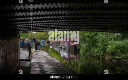Londra, Regno Unito: Case galleggianti a Blomberg Road Moorings sul Regent's Canal a Londra, parte dell'area conosciuta come Little Venice. Visto da sotto un ponte. Foto Stock