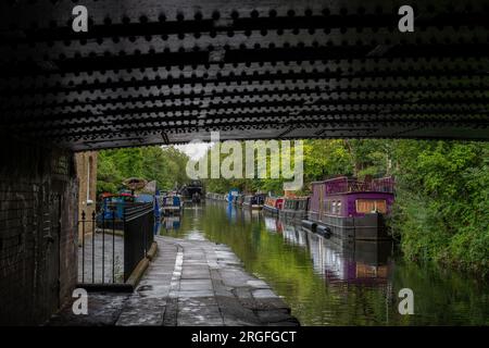 Londra, Regno Unito: Case galleggianti a Blomberg Road Moorings sul Regent's Canal a Londra, parte dell'area conosciuta come Little Venice. Visto da sotto un ponte. Foto Stock