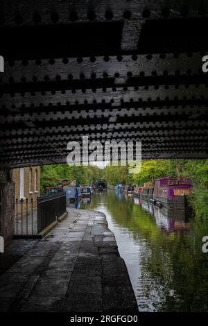 Londra, Regno Unito: Case galleggianti a Blomberg Road Moorings sul Regent's Canal a Londra, parte dell'area conosciuta come Little Venice. Visto da sotto un ponte. Foto Stock