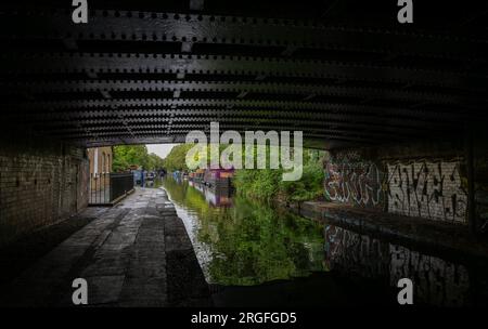 Londra, Regno Unito: Case galleggianti a Blomberg Road Moorings sul Regent's Canal a Londra, parte dell'area conosciuta come Little Venice. Visto da sotto un ponte. Foto Stock