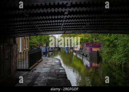 Londra, Regno Unito: Case galleggianti a Blomberg Road Moorings sul Regent's Canal a Londra, parte dell'area conosciuta come Little Venice. Visto da sotto un ponte. Foto Stock