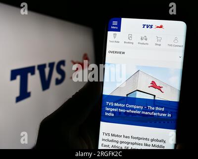 Persona che possiede il cellulare con il sito Web dell'azienda motociclistica TVS Motor Company Limited sullo schermo con logo. Concentrarsi sul centro del display del telefono. Foto Stock